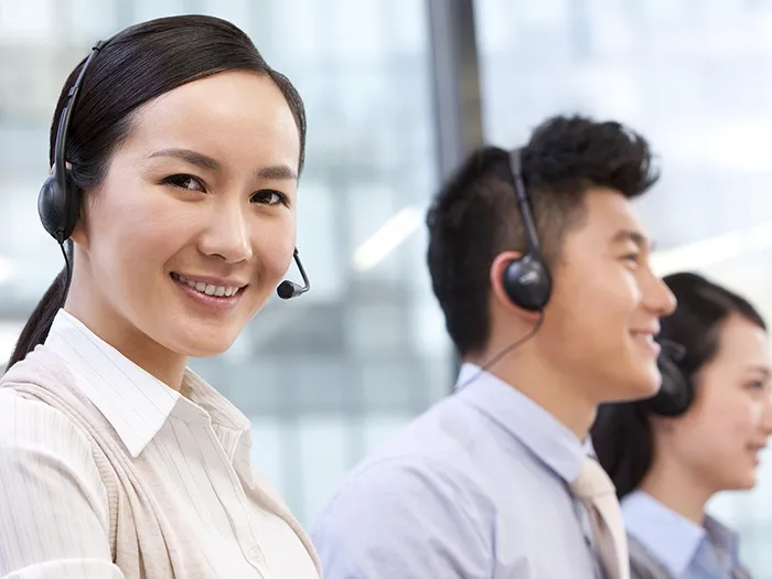 Three customer service representatives wearing headsets are smiling.