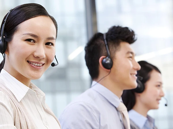 Three customer service representatives wearing headsets and smiling