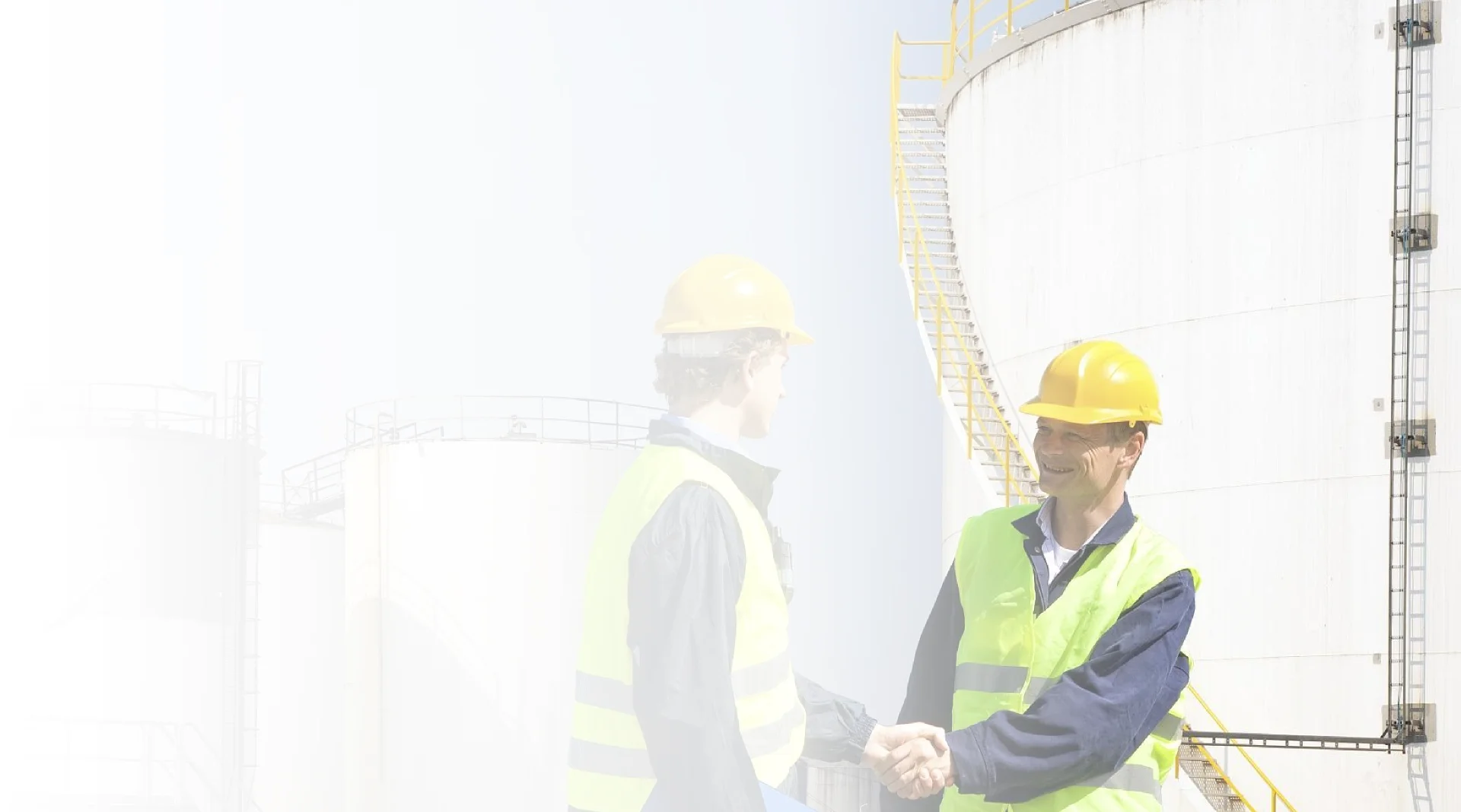 Two people wearing safety helmets are shaking hands.