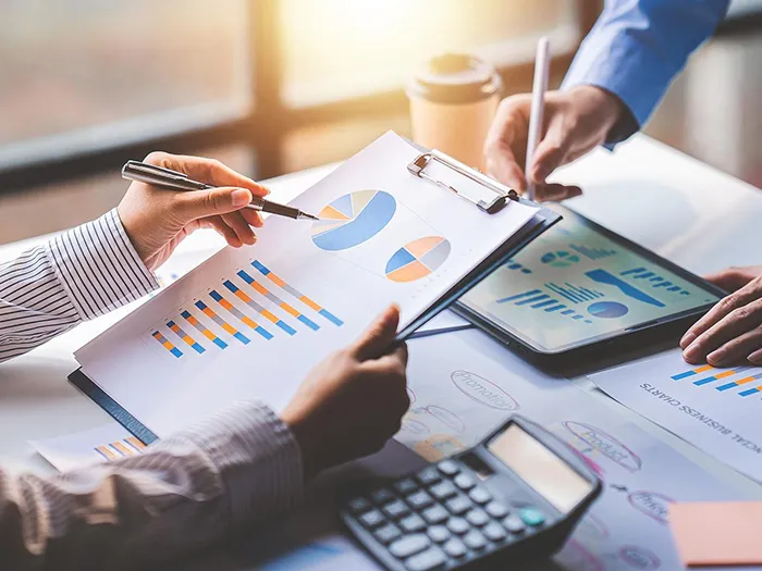 Two employees holding pens and reports are discussing with each other.
