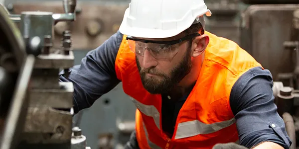 A worker wearing a safety helmet is operating machinery.
